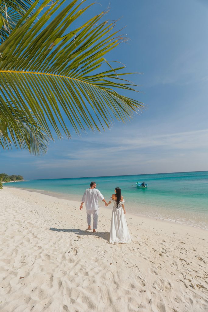 Se marier en Polynésie : une expérience à vivre à deux Couple de mariés marchant main dans la main sur une plage de Polynésie française, symbole d’un mariage intime et serein au bout du monde.