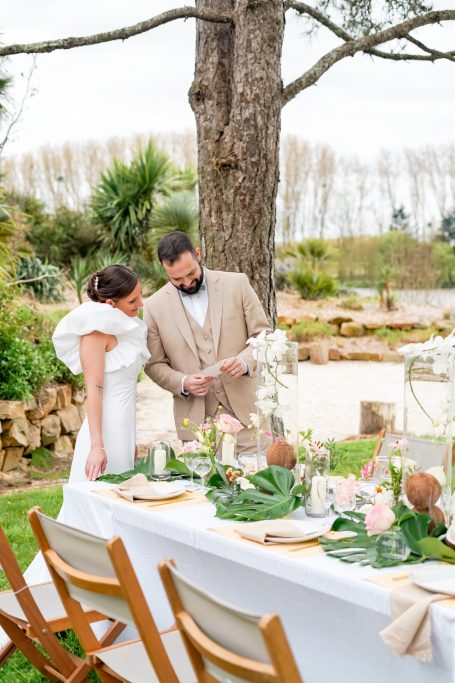 Un couple en train de préparer une table de mariage décorée en extérieur.