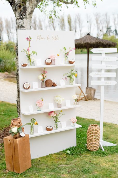 Étagère décorative avec fleurs et objets naturels, entourée de verdure.