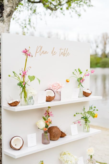 Vase décoratif avec fleurs colorées sur étagère près de l'eau, ambiance romantique.