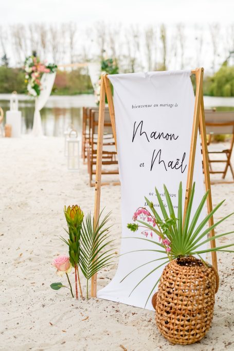 Bannière de mariage avec les prénoms, plantes en pot et décor en bord de lac.